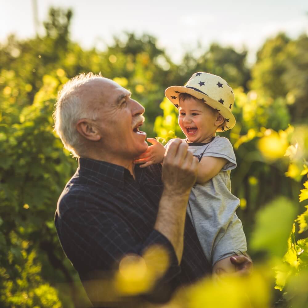 A grandfather holds his grandson in the garden. He feels good knowing his estate plan will provide for his grandson.