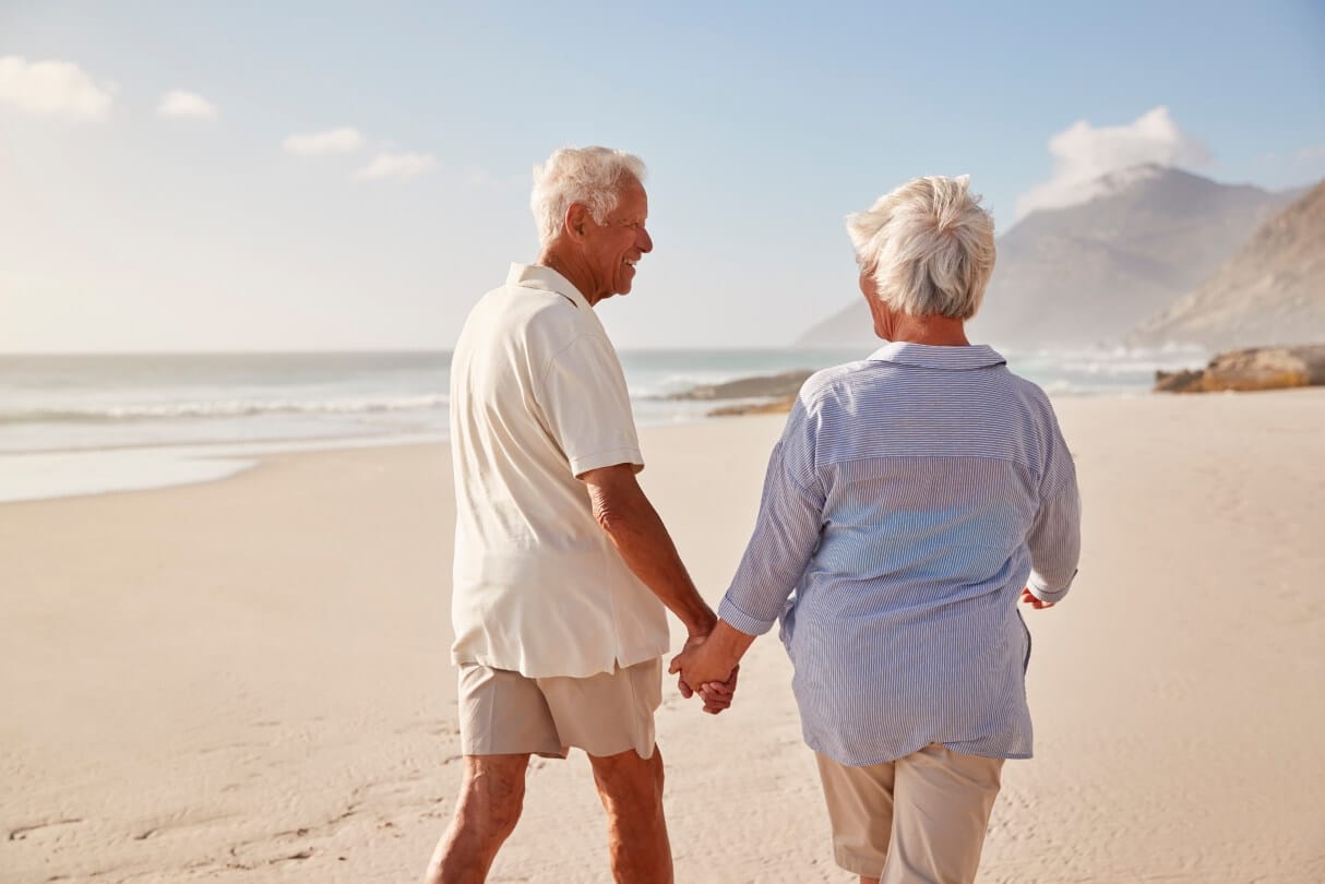 A retired couple enjoy a nice walk on the beach on a sunny day