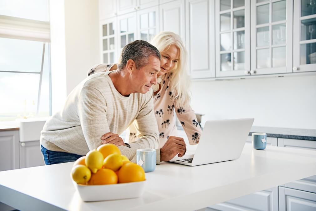 Senior couple reviewing finances on a laptop at home, discussing whether to hire a financial advisor.